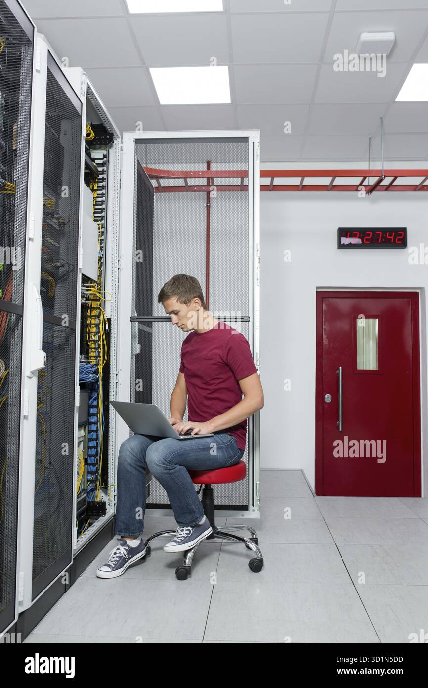 Jeune homme est debout à côté du châssis et l'équipement informatique Banque D'Images