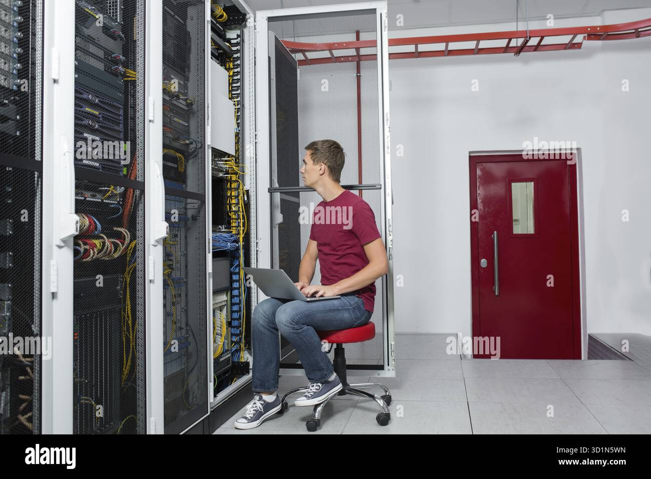 Jeune homme est debout à côté du châssis et l'équipement informatique Banque D'Images