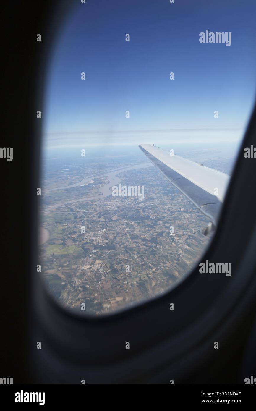 Terre, océan et aile d'avion vue depuis la fenêtre de l'avion Banque D'Images