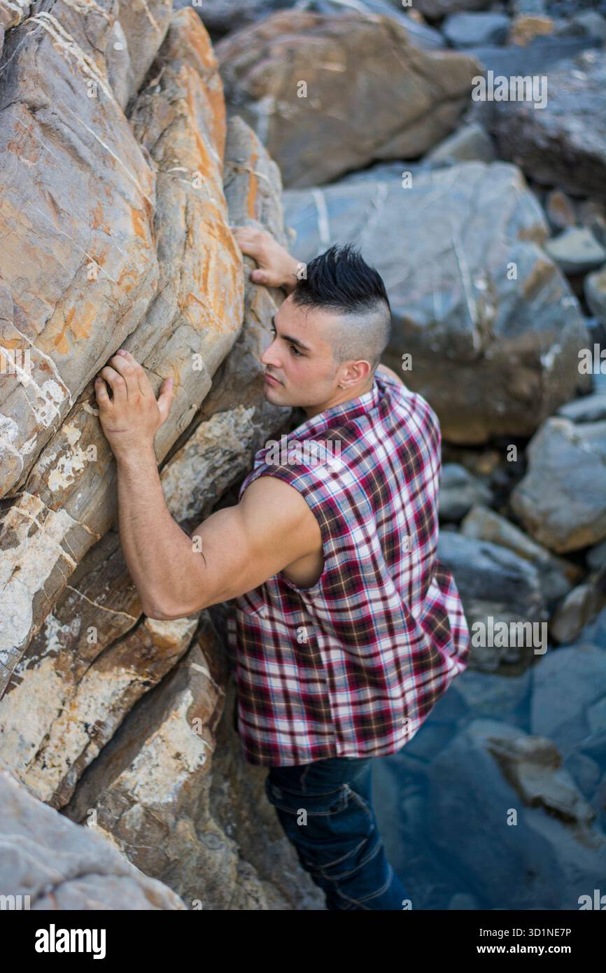 Bel homme grimpant un rocher à la rivière Banque D'Images