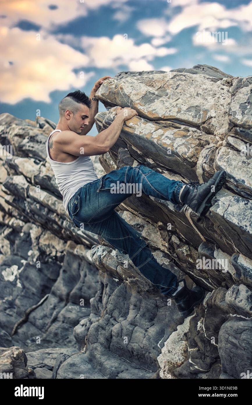Bel homme grimpant un rocher à la rivière Banque D'Images