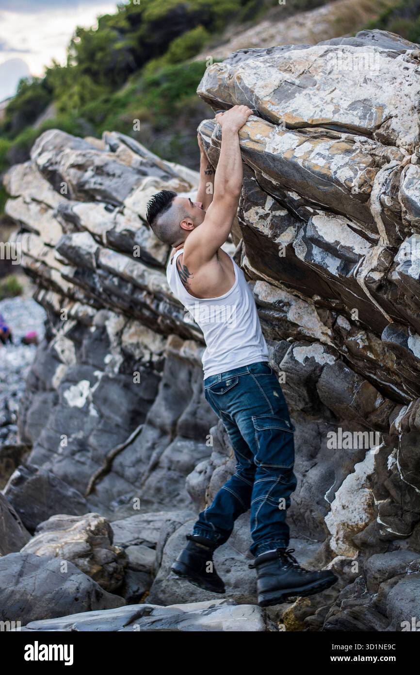 Bel homme grimpant un rocher à la rivière Banque D'Images
