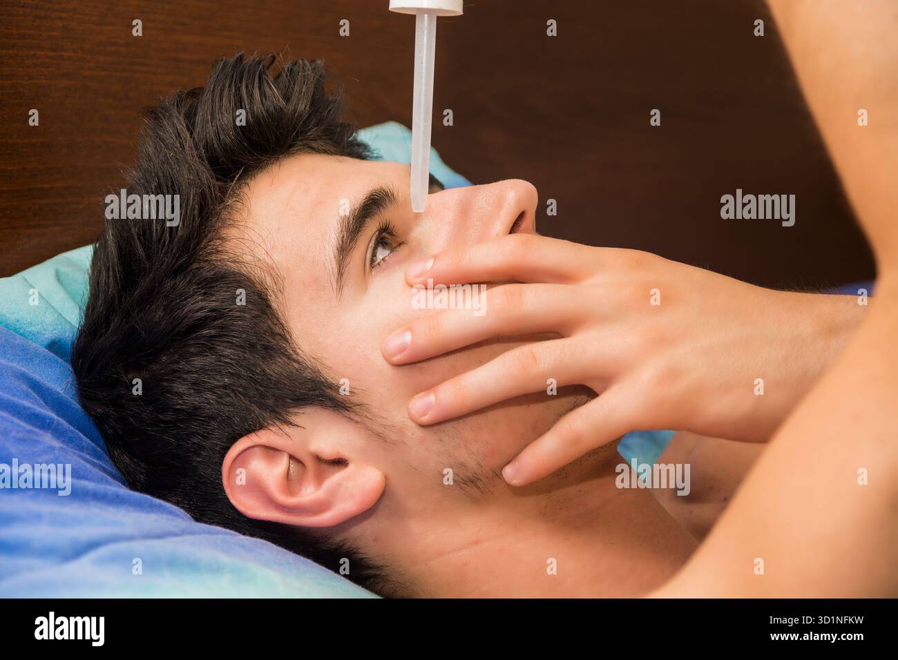 Beau jeune homme qui laisse tomber des médicaments dans l'oeil Banque D'Images