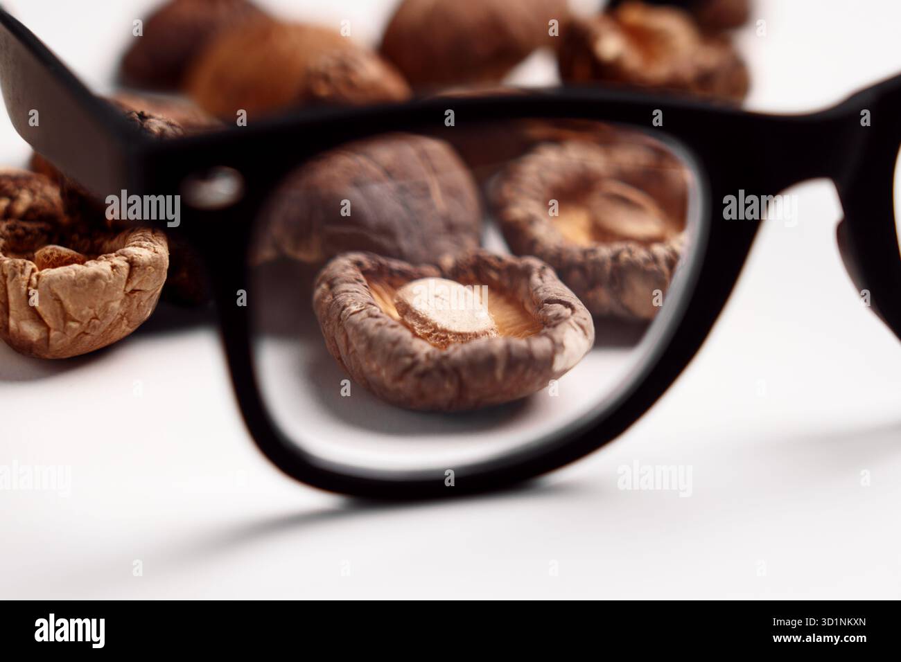 Vue des champignons shiitake séchés à travers des lunettes. Ingrédients alimentaires. Contrôle qualité et concept d'exploration culinaire Banque D'Images