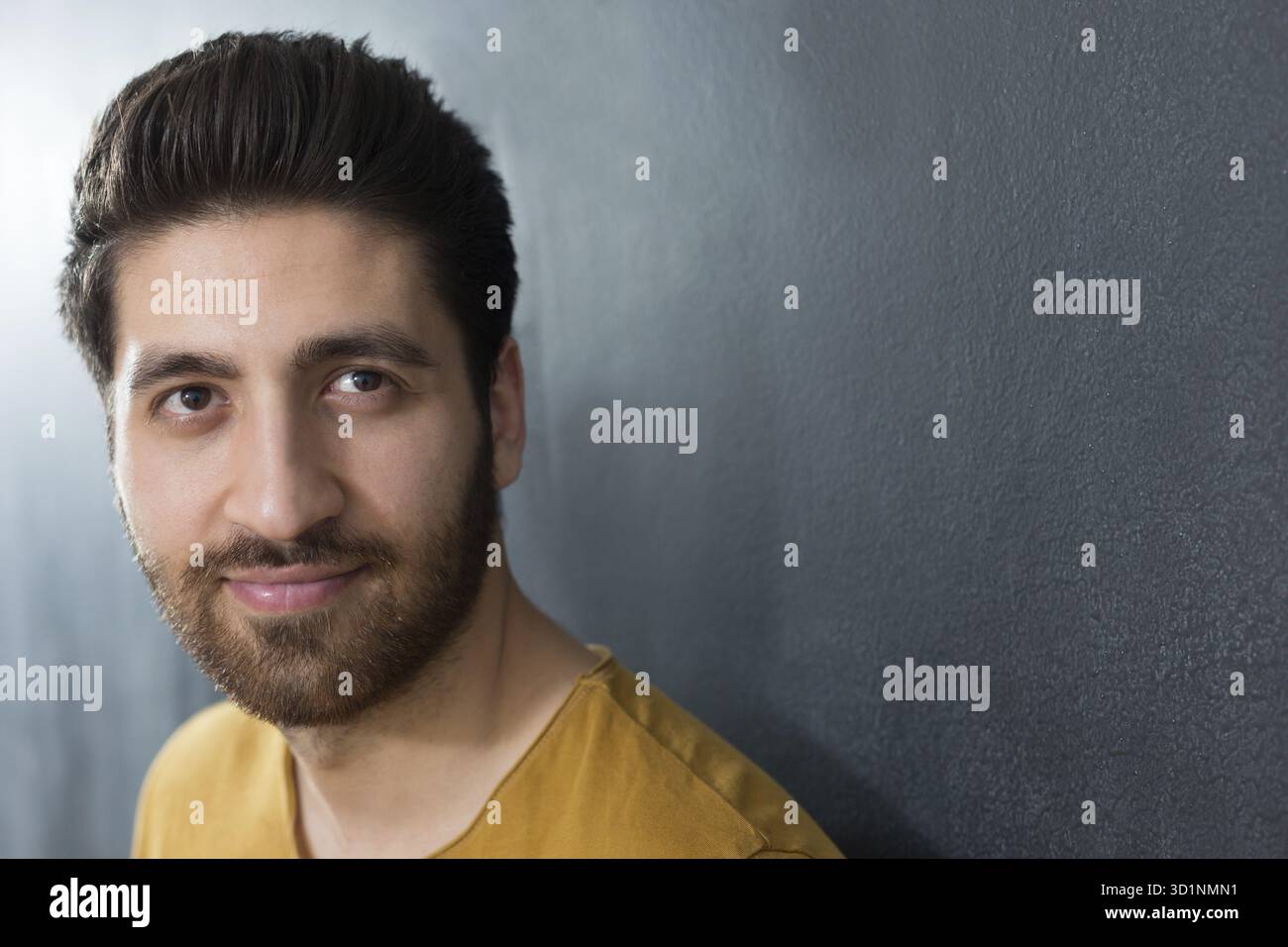 Portrait studio d'un homme adulte caucasien au début des années 30 sur fond gris. Il semble être de bonne humeur, regardant la caméra avec un grand aussi Banque D'Images