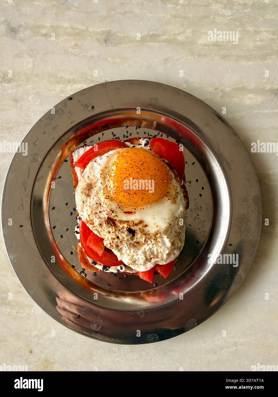 Sandwich aux œufs frits avec tomate et sésame noir sur une assiette en métal - Image de stock capturée avec un smartphone