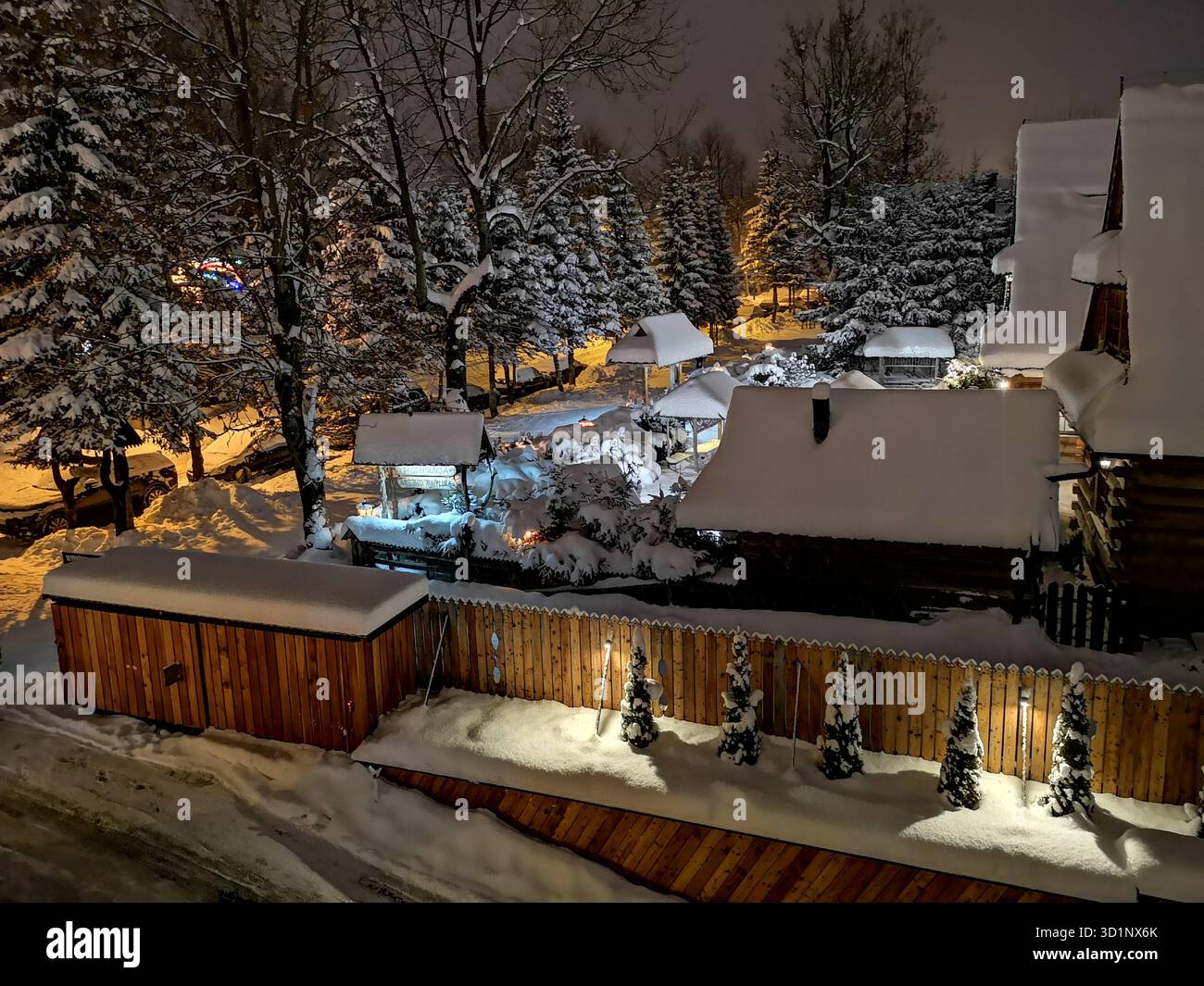 Nuit d’hiver sur la rue Piłsudskiego, Zakopane, Pologne – arbres et bâtiments enneigés dans la pittoresque station balnéaire des montagnes des Tatras. - Image de stock capturée avec un smartphone