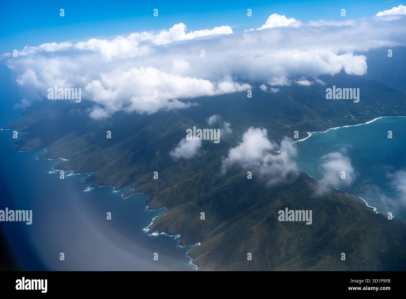 Vue aérienne époustouflante de Hiva Oa dans les îles Marquises, Polynésie française, avec des côtes accidentées, des eaux turquoises, des falaises spectaculaires, et des montagnes verdoyantes sous des nuages éparpillés Banque D'Images