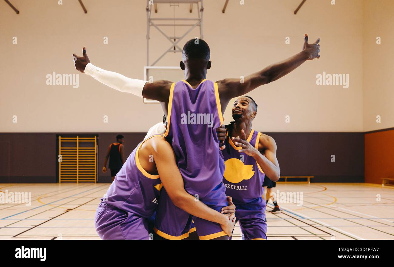 Jeunes joueurs de basket-ball énergiques en action sur un terrain couvert, mettant en valeur le travail d'équipe et l'esprit de compétition, mettant l'accent sur l'esprit sportif et athlétique Banque D'Images