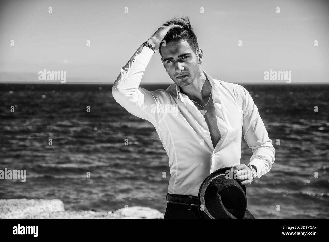 Bel homme en chemise blanche et chapeau sur la plage Banque D'Images