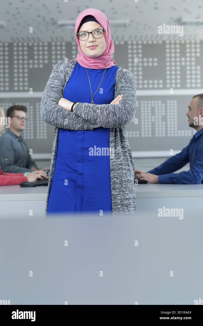 Jeune femme islamique avec un groupe d'élèves habillés de vêtements traditionnels à l'intérieur du cadre scolaire Banque D'Images