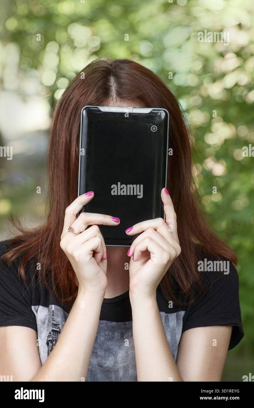 La femme rousse se cacher son visage par tablet PC Banque D'Images