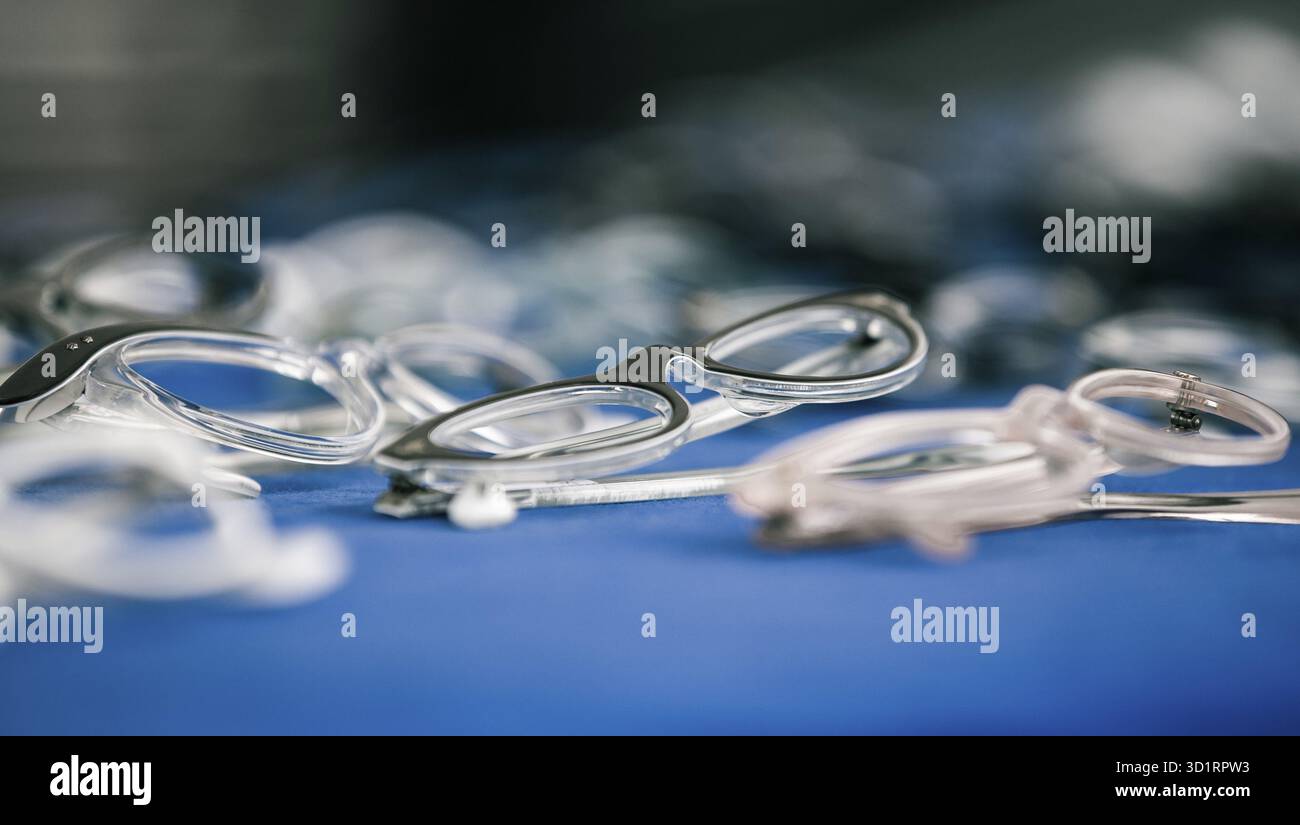 Une collection de différentes lunettes et montures dispersées sur une surface bleue, présentant divers styles et designs, Allemagne Banque D'Images
