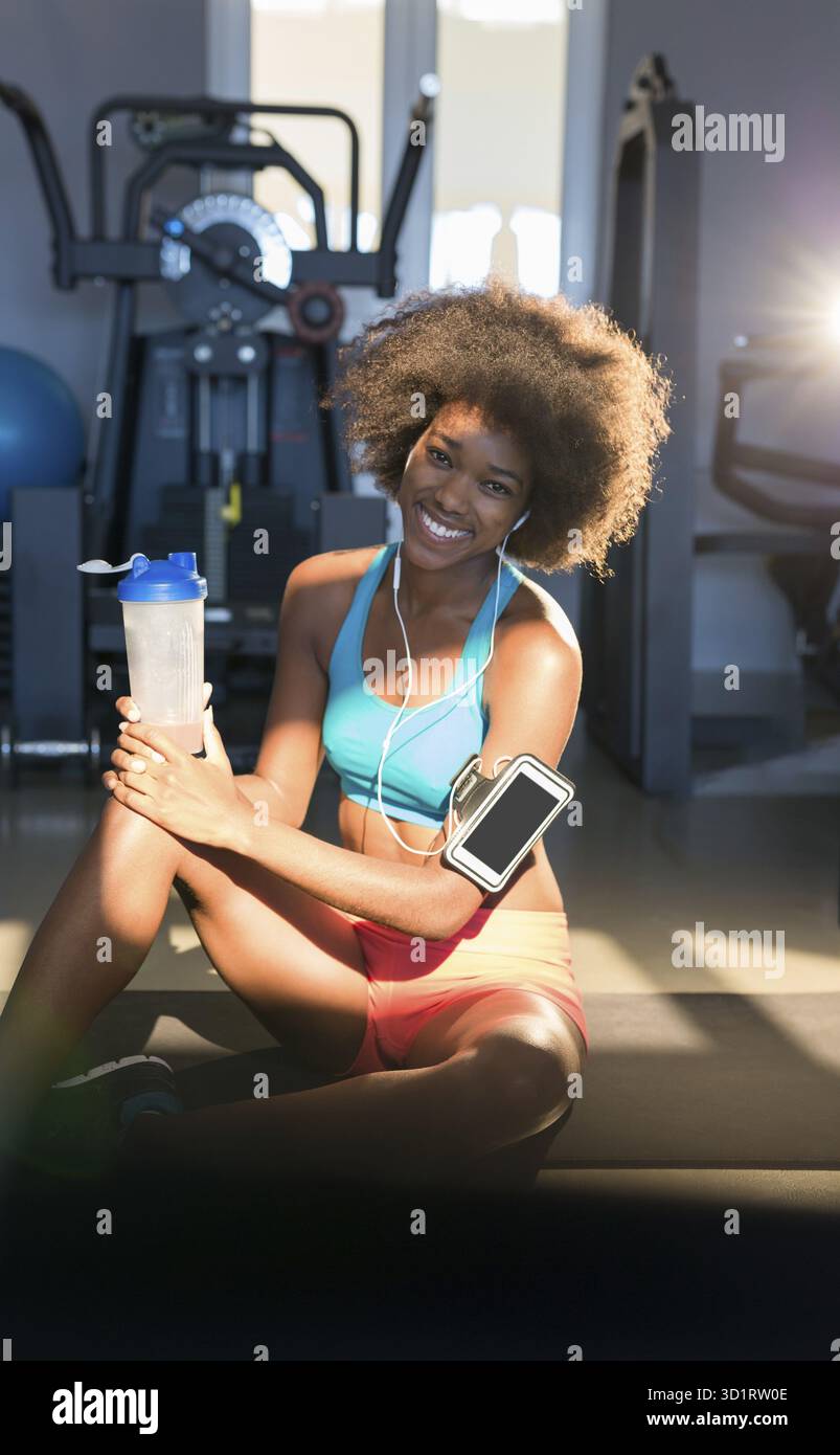 Portrait d'une femme en forme épuisée se relaxant après l'entraînement avec des poids libres, charmante fille ayant un repos après la formation de fitness au gymnase Banque D'Images