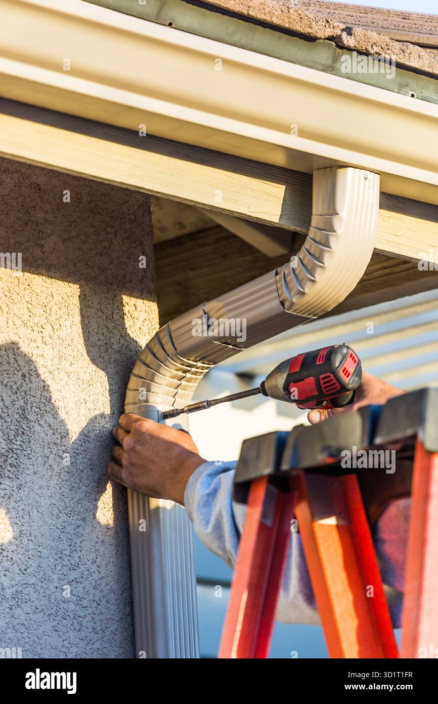 Employé fixant la gouttière en aluminium et le bec verseur à la structure d'affichage de la maison Banque D'Images