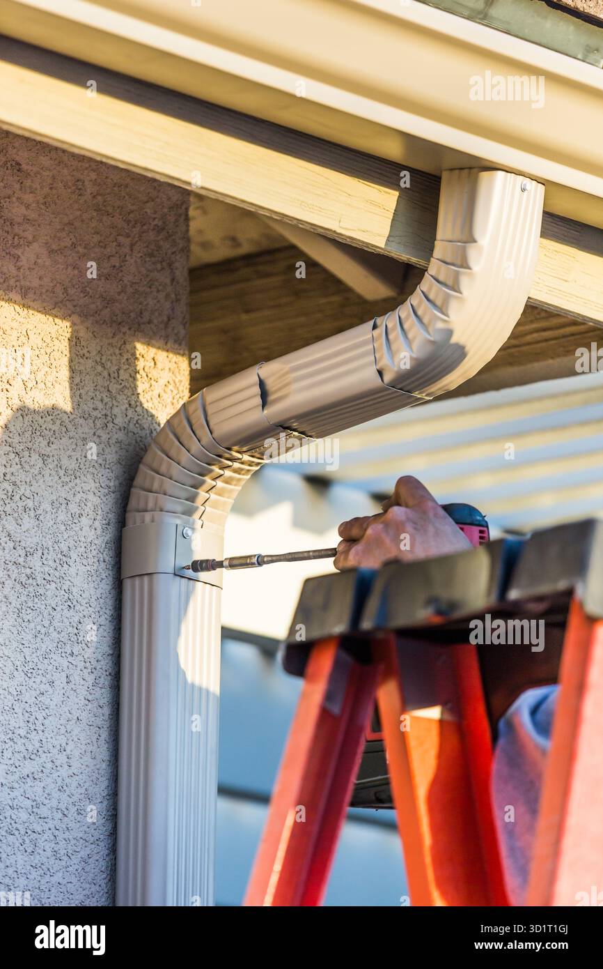 Employé fixant la gouttière en aluminium et le bec verseur à la structure d'affichage de la maison Banque D'Images