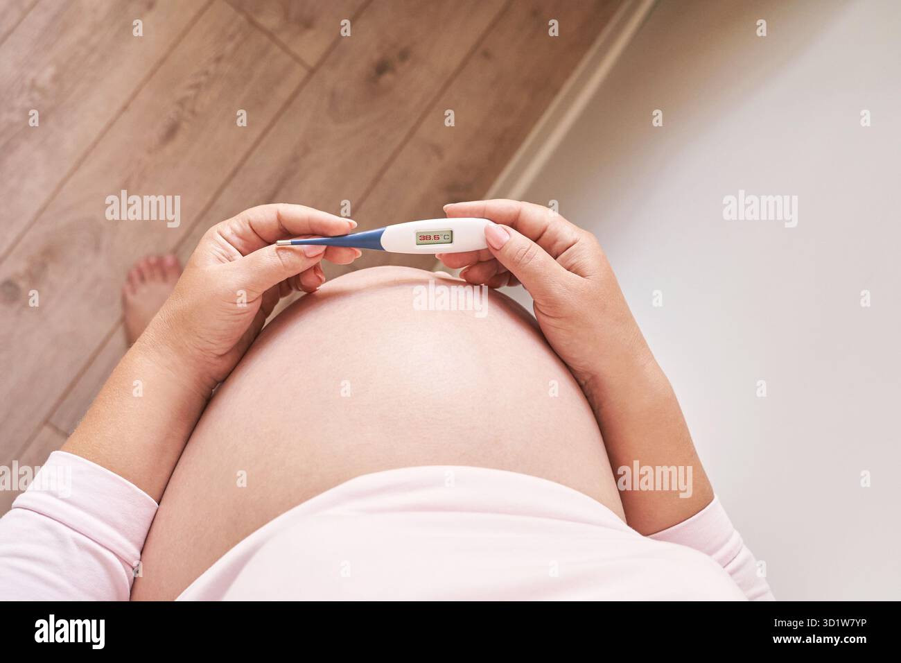 Femme enceinte tenant un thermomètre de fièvre. Traitement de la grippe. Corps humain. Femme malade à la maison Banque D'Images