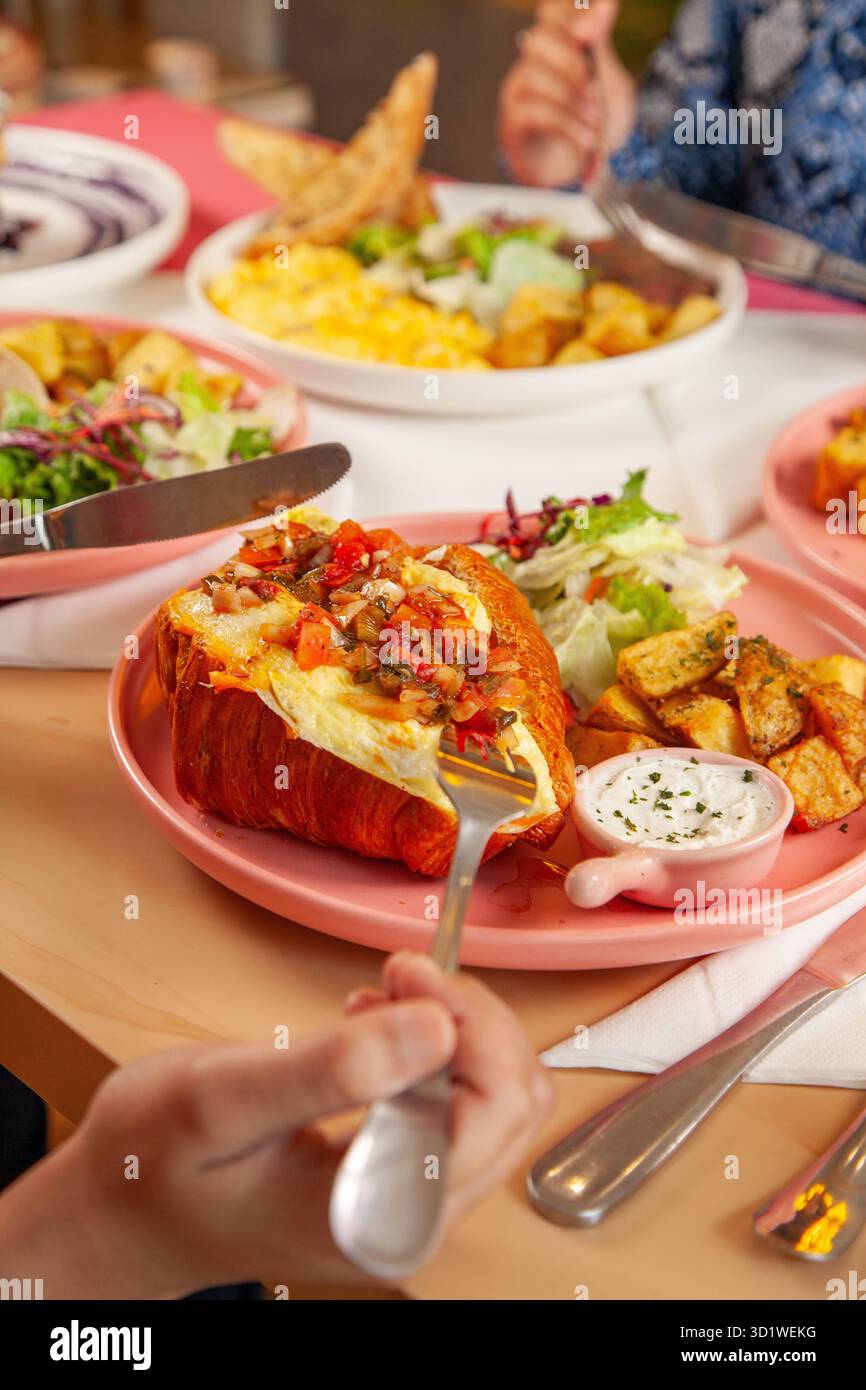 Femme appréciant le brunch petit déjeuner sandwich croissant avec café latte glacé froid. Banque D'Images