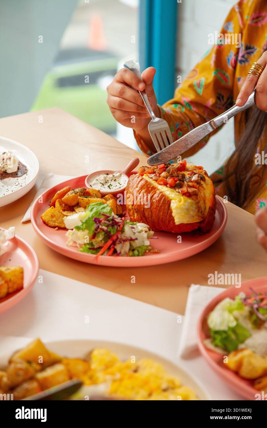 Femme appréciant le brunch petit déjeuner sandwich croissant avec café latte glacé froid. Banque D'Images