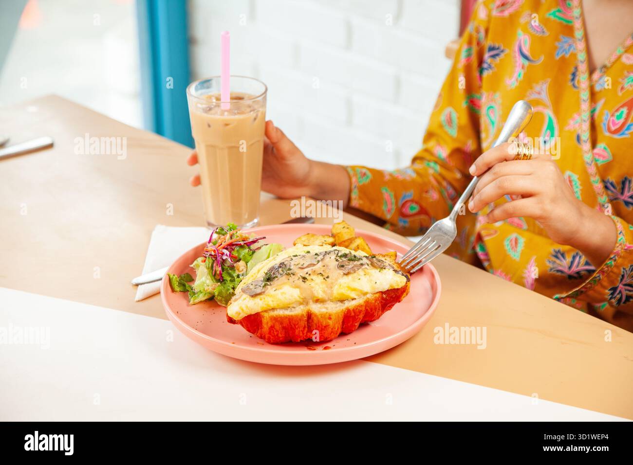 Femme appréciant le brunch petit déjeuner sandwich croissants avec café latte glacé froid. Banque D'Images