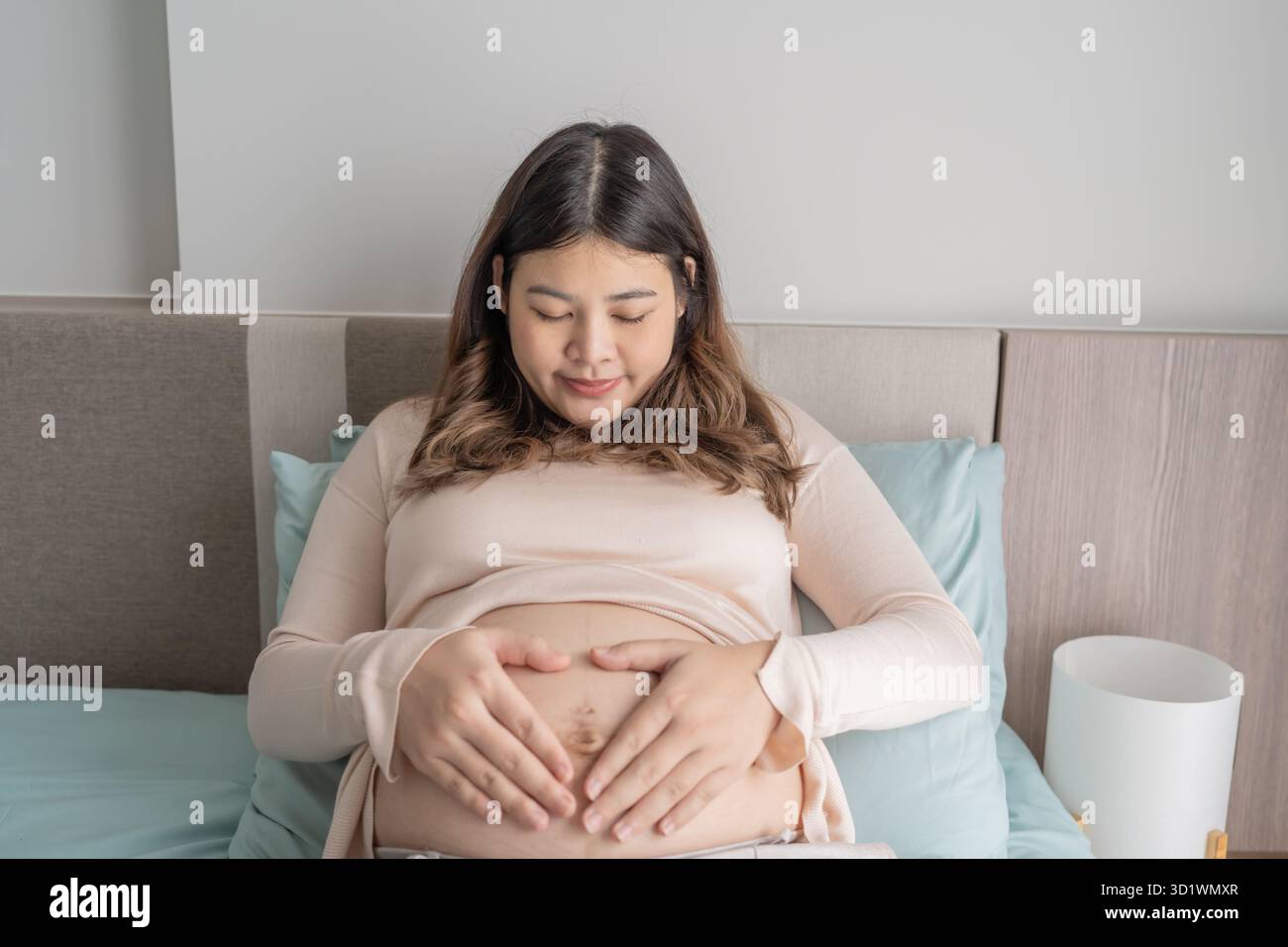 Femme asiatique enceinte tient les mains sur le ventre touchant son bébé se souciant de sa santé belle femme enceinte heureuse humeur tendre Banque D'Images