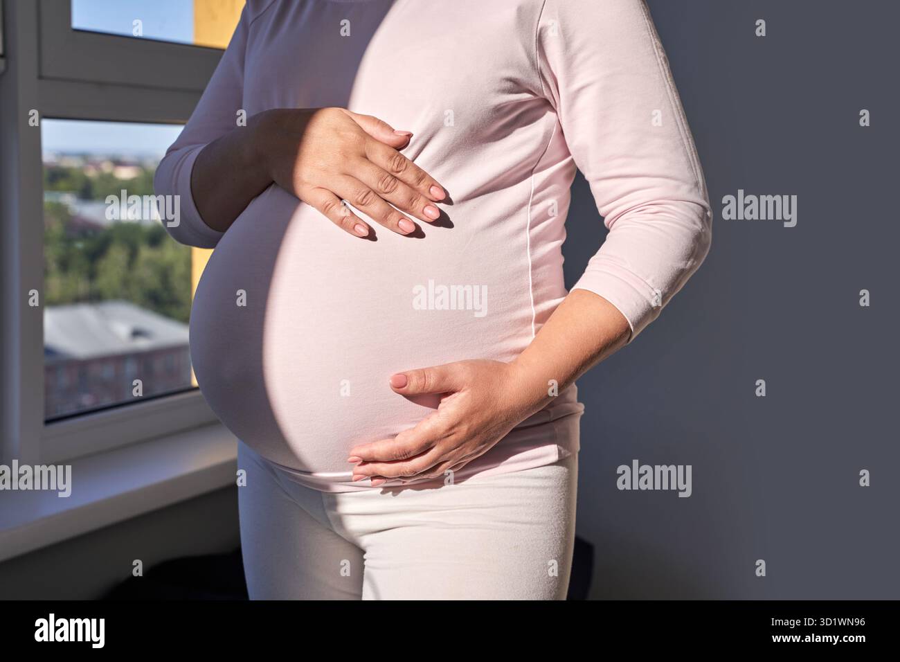 Tendre anticipation : la mère attend la grossesse voyage ensoleillé fenêtre Banque D'Images