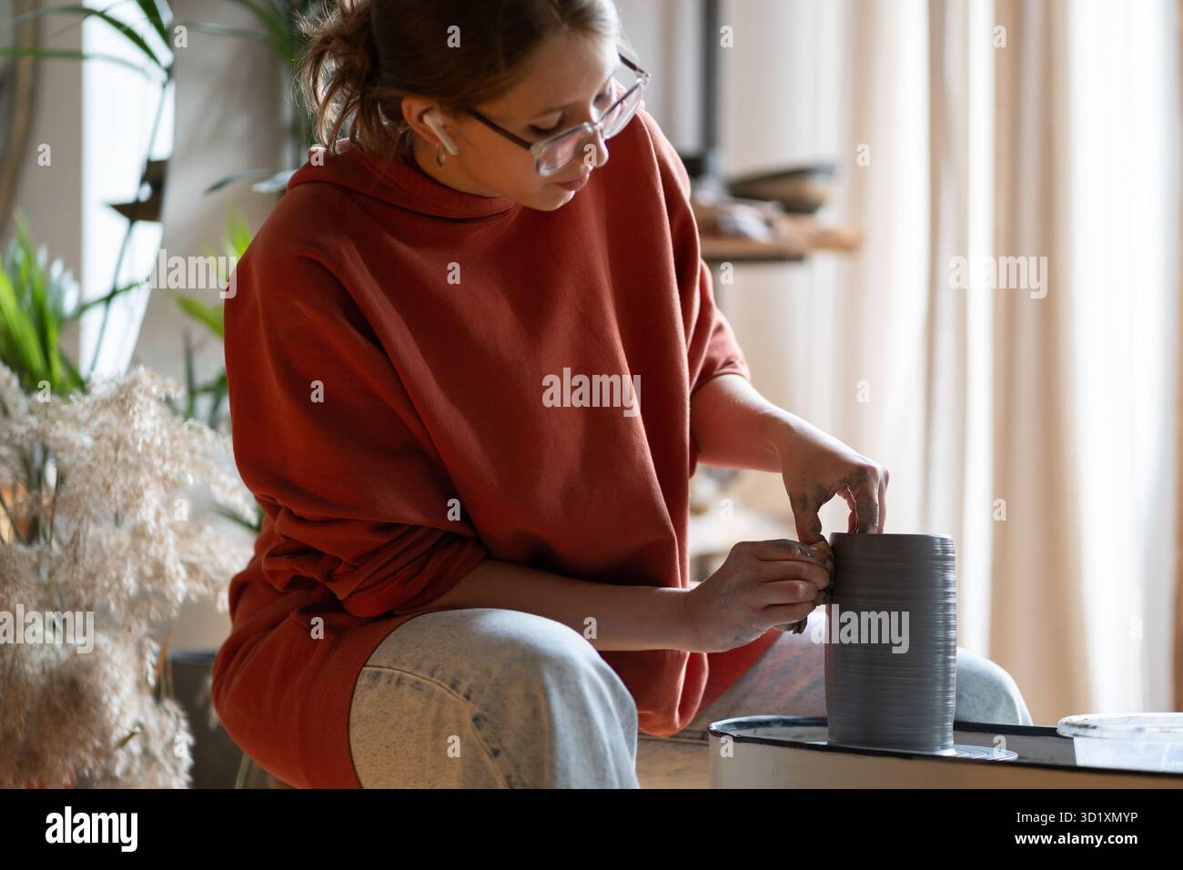 L'artisan focalisé forme soigneusement le vaisseau en argile tournant sur la roue de potier. Concept de passe-temps Banque D'Images