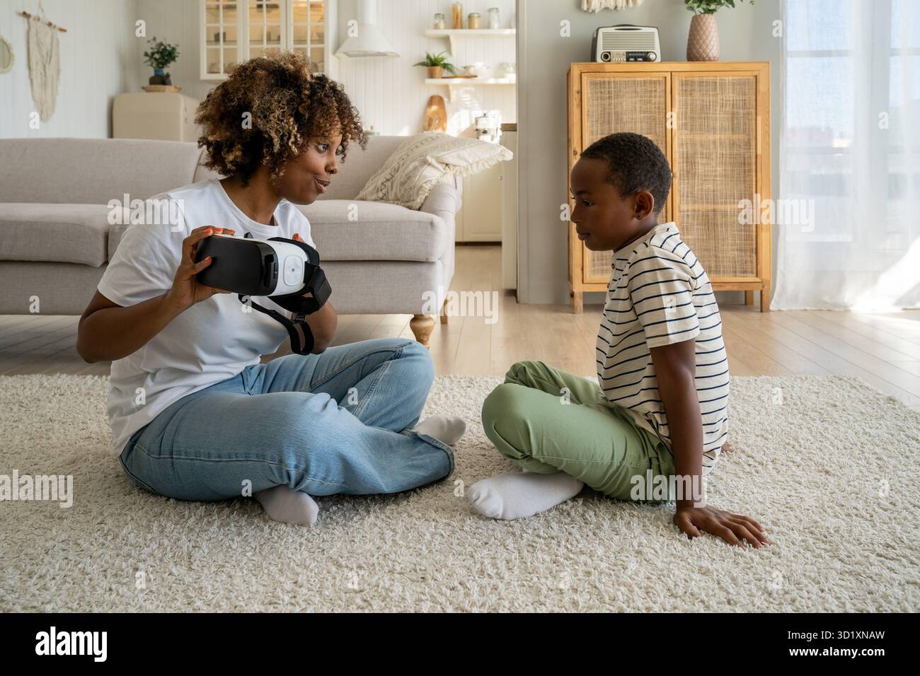 Mère et fils de la famille afro-américaine moderne assis sur le sol avec un casque de réalité virtuelle Banque D'Images