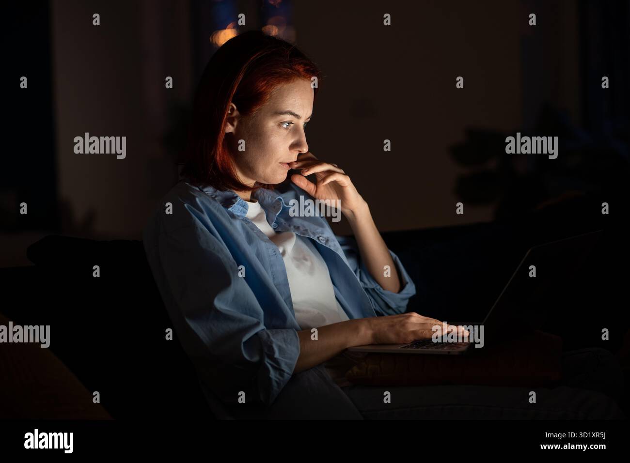 Femme pigiste focalisée regardant l'écran d'ordinateur portable la nuit travaillant de la maison. Banque D'Images