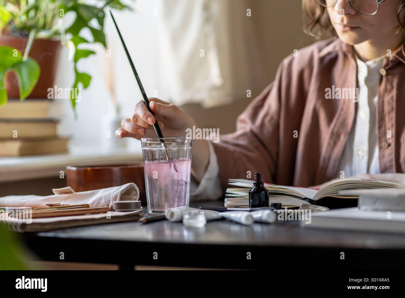 L'artiste peint avec des acryliques nettoie la brosse dans le verre transparent de l'eau. Espace esthétique pour la créativité Banque D'Images