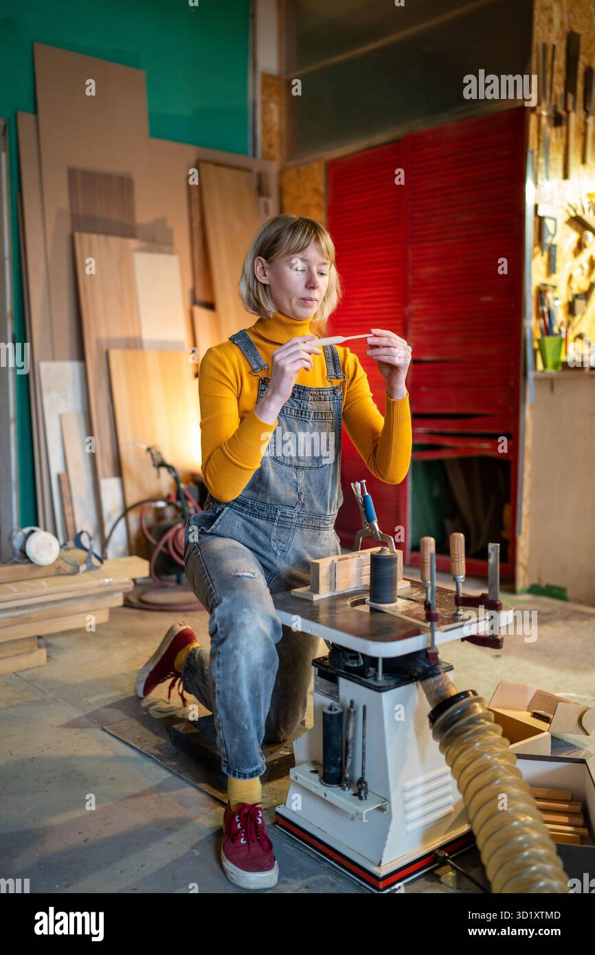 Un menuisier qualifié forme des ébauches de couteau en bois sur le tour, en examinant attentivement l'artisanat en studio Banque D'Images