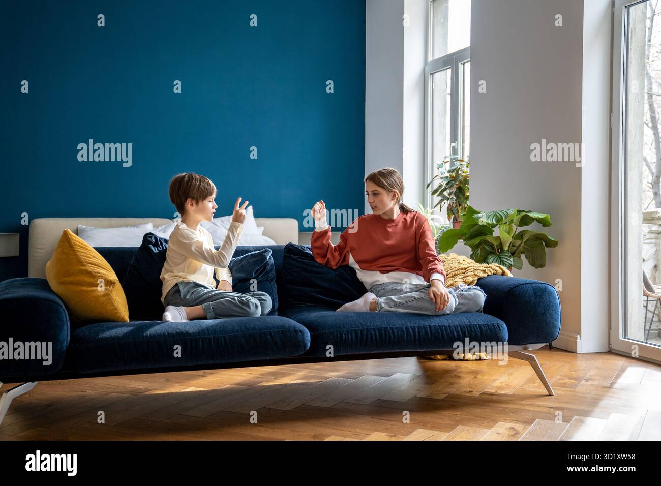 Enfants frères et sœurs assis sur un canapé jouer amusant jeu pour enfants ciseaux de papier de roche Banque D'Images