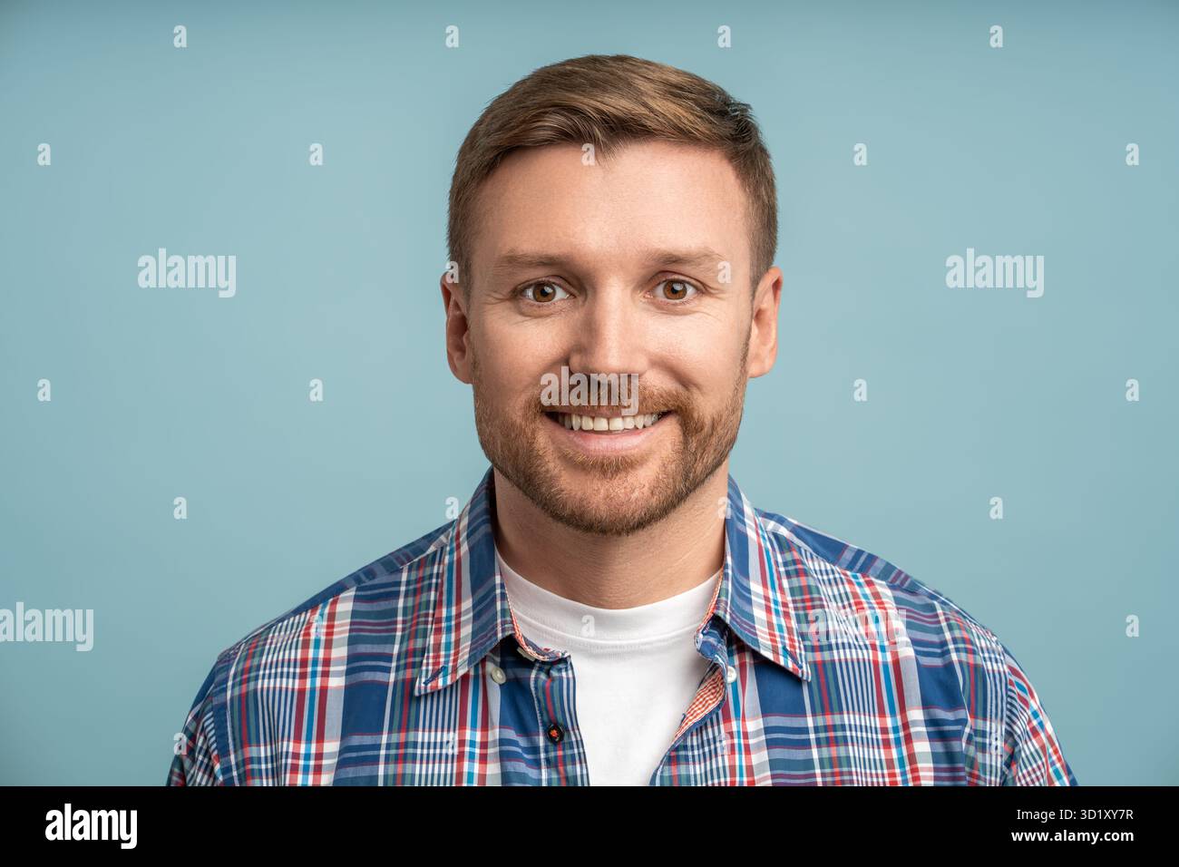 Portrait positif caucasien amical homme barbu regardant la caméra souriant sur fond bleu. Banque D'Images