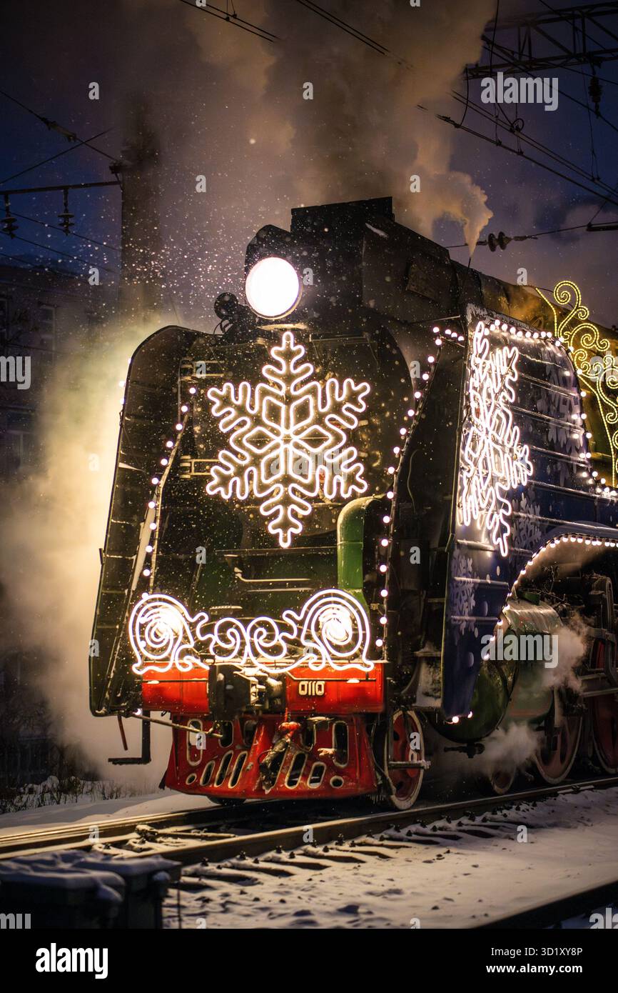 Train à vapeur rétro de Noël la nuit dans la ville la veille de Noël et le nouvel an en Russie. Banque D'Images