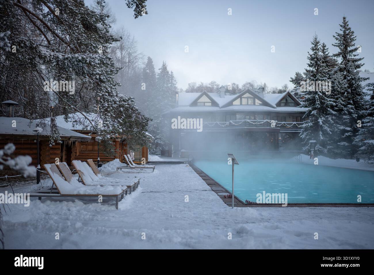 Piscine en plein air avec eau chaude, chaises longues et bain russe en bois par temps froid Banque D'Images