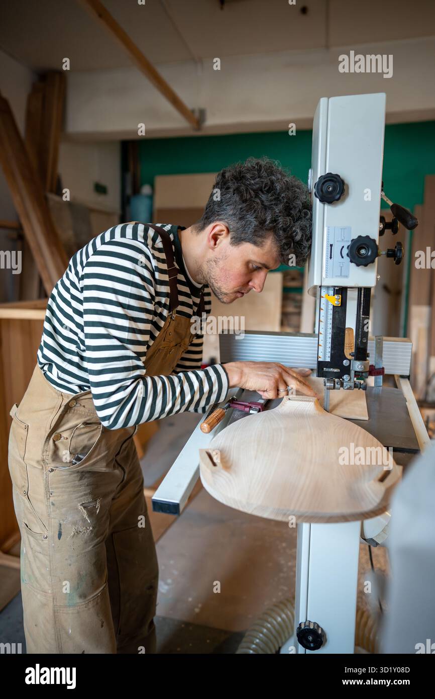 Atelier de menuiserie, maître artisan travaille sur scie sauteuse. Menuisier sculpté sur bois avec équipement spécial Banque D'Images