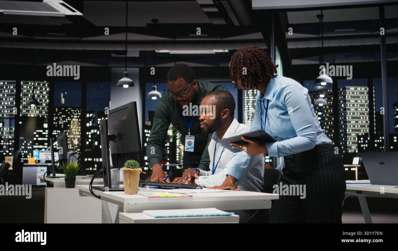 Groupe d'employés noirs faisant un travail d'équipe sur une tâche importante tard dans la nuit, collaborant à l'élaboration d'une nouvelle stratégie de développement après les heures de travail. Examiner les informations pour améliorer l'efficacité. Banque D'Images