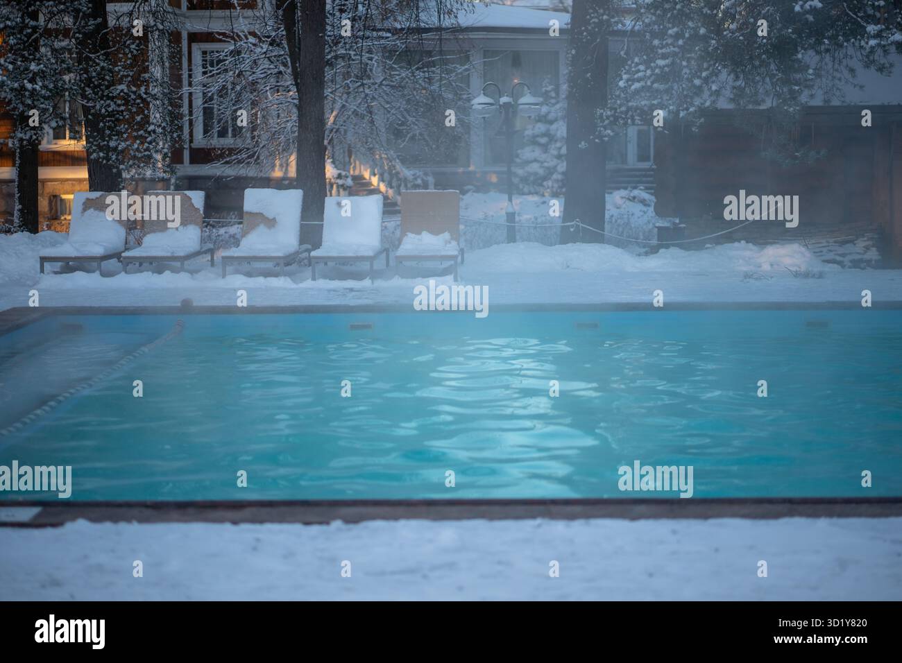 Piscine en plein air avec eau chaude, chaises longues par temps froid. Station thermale de bien-être d'hiver . Banque D'Images