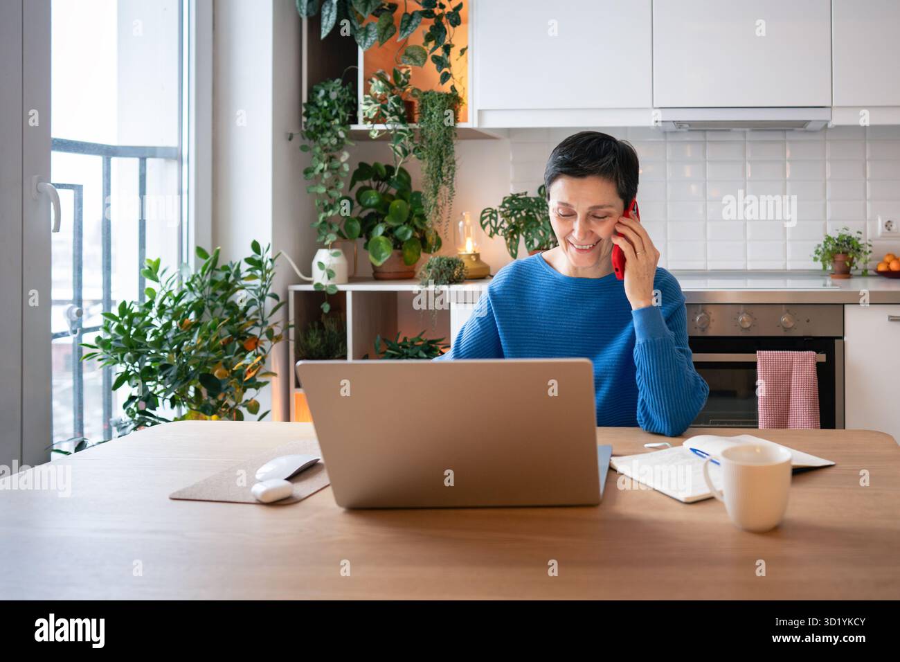 Leadership à distance. Femme mature souriant, traitant l'appel d'affaires et travaillant sur ordinateur portable à partir du bureau à domicile Banque D'Images