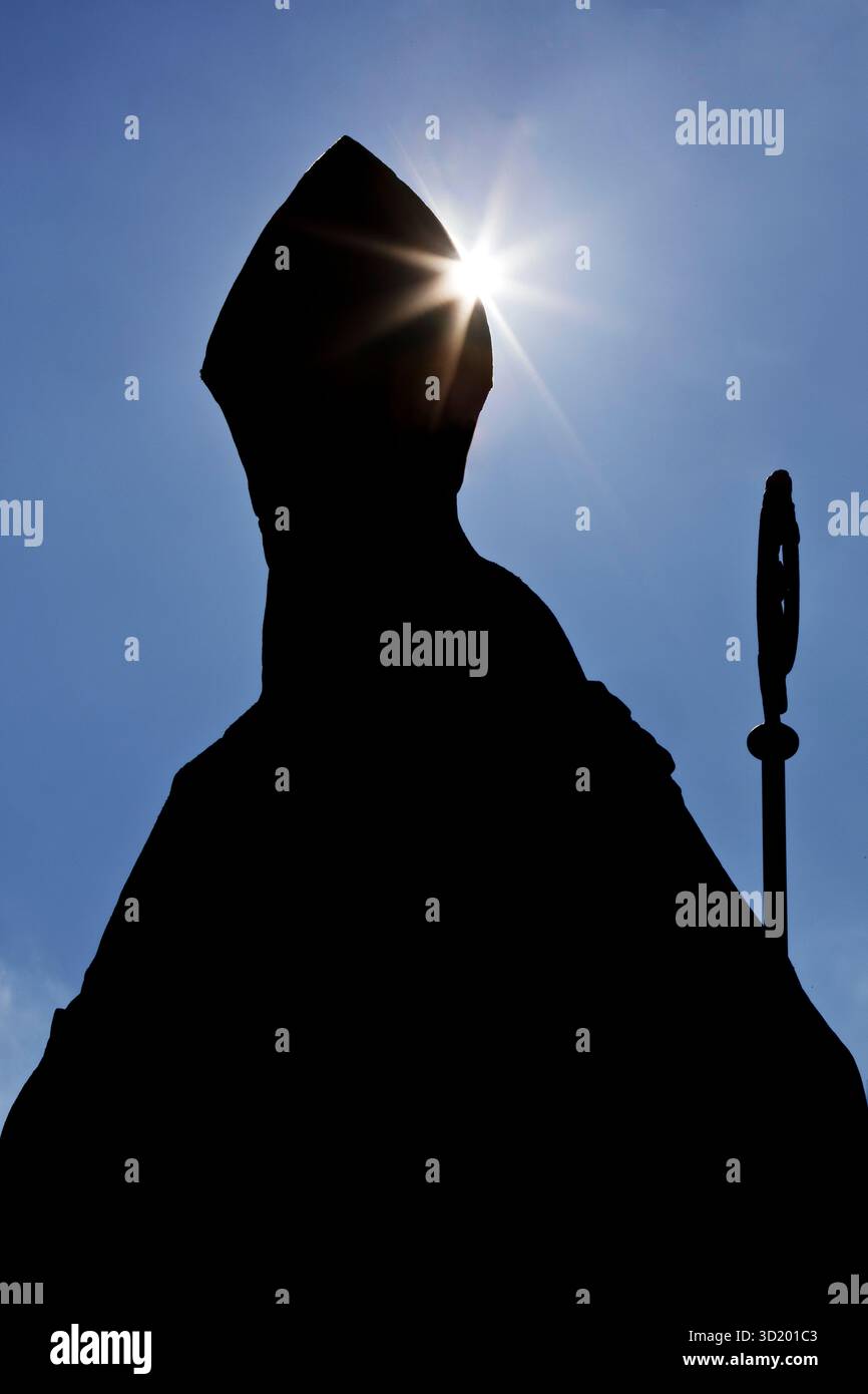 Évêque catholique anonyme avec mitre et crosier comme silhouette en contre-jour, photo symbolique Banque D'Images