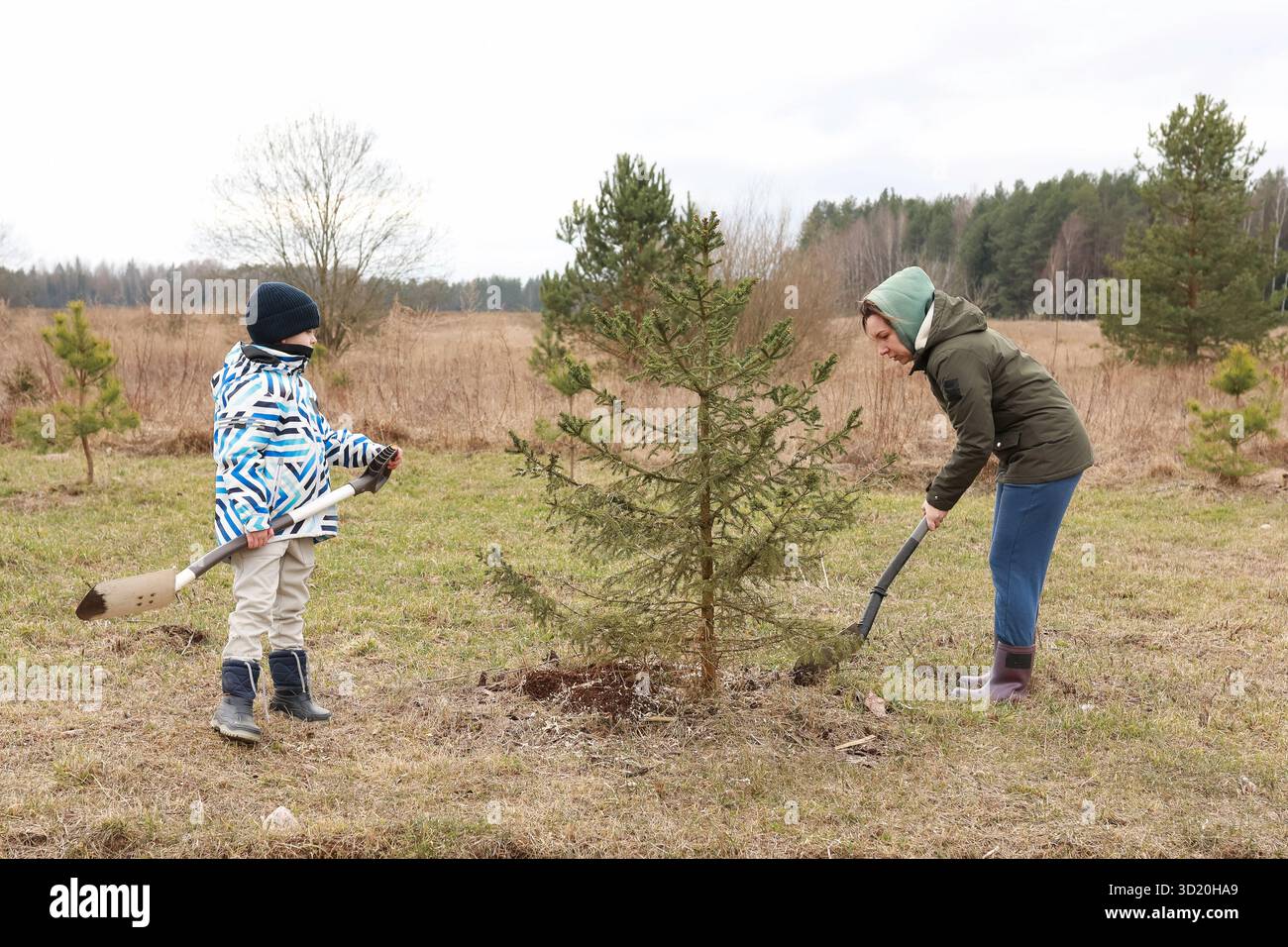 Enfants plantant un arbre dans une région rurale au début du printemps, embrassant la nature et la gérance de l'environnement Banque D'Images