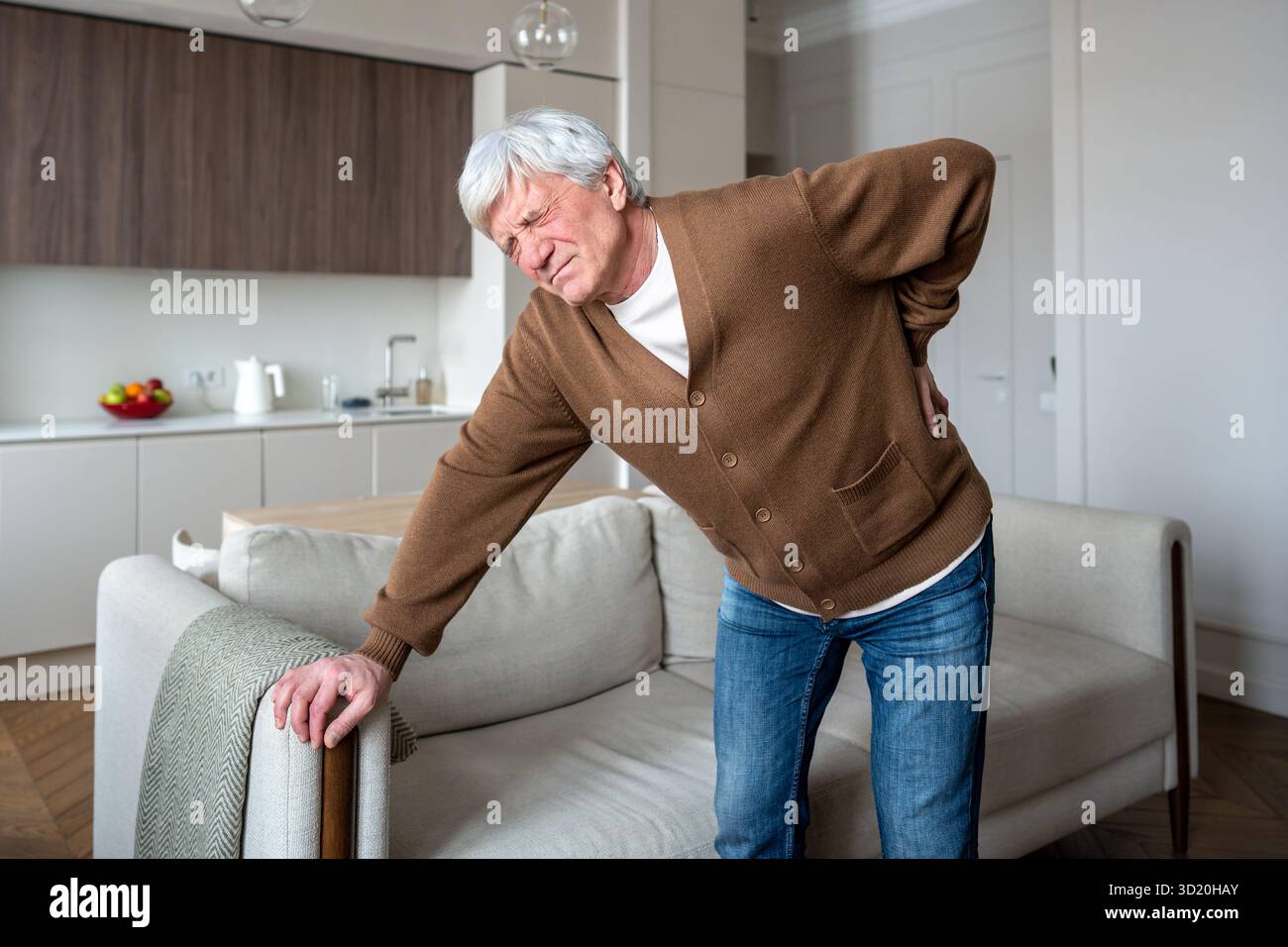 Plisser l'homme âgé souffre seul saisissant la colonne vertébrale douloureuse avec une mobilité limitée dans la maison vide Banque D'Images