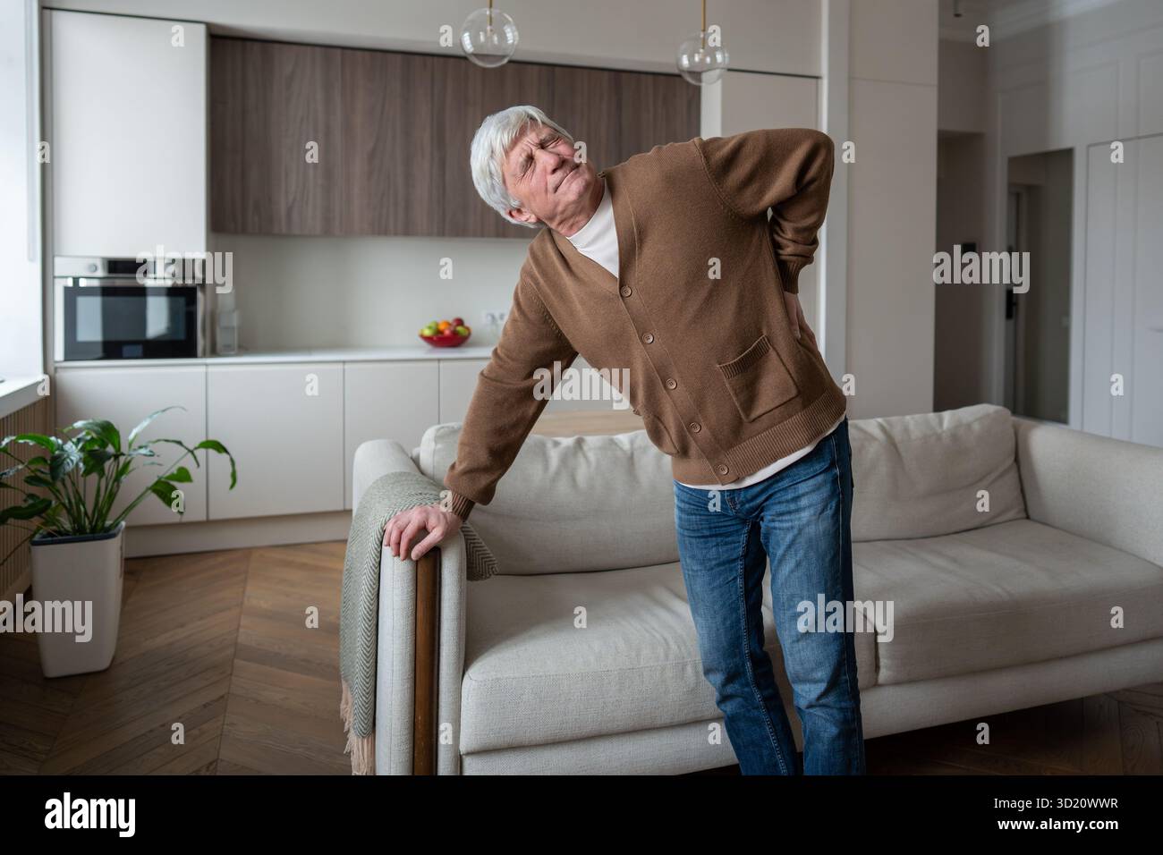 Grimaces angoissées de retraités âgés en douleur de mal de dos colique rénale, appuyé sur le canapé Banque D'Images