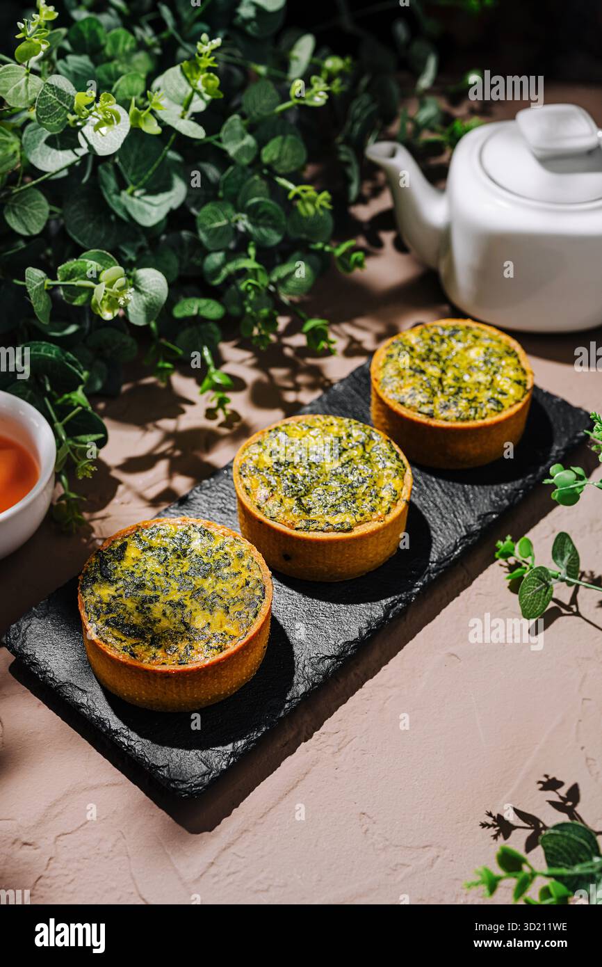 Délicieuses tartes aux herbes servies avec du thé sur une table rustique avec des accents de verdure Banque D'Images