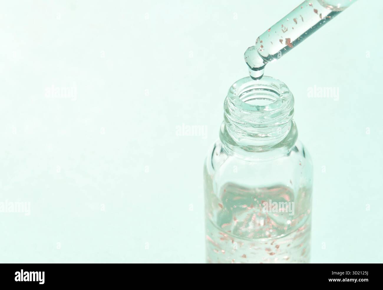 Flacon compte-gouttes en verre transparent avec du liquide et des bulles sur un vert clair Banque D'Images