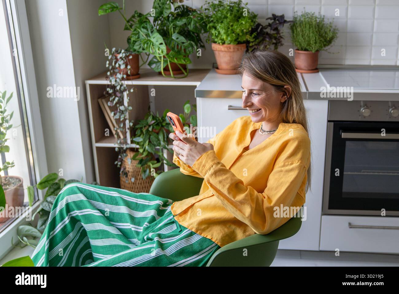 Femme positive souriante ravie avec téléphone portable, ayant un appel vidéo en ligne avec des amis, des parents Banque D'Images