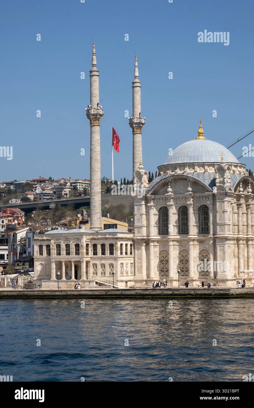 Mosquée Ortaköy s'élevant du Bosphore à Istanbul sous un ciel dégagé avec drapeau turc agitant Banque D'Images