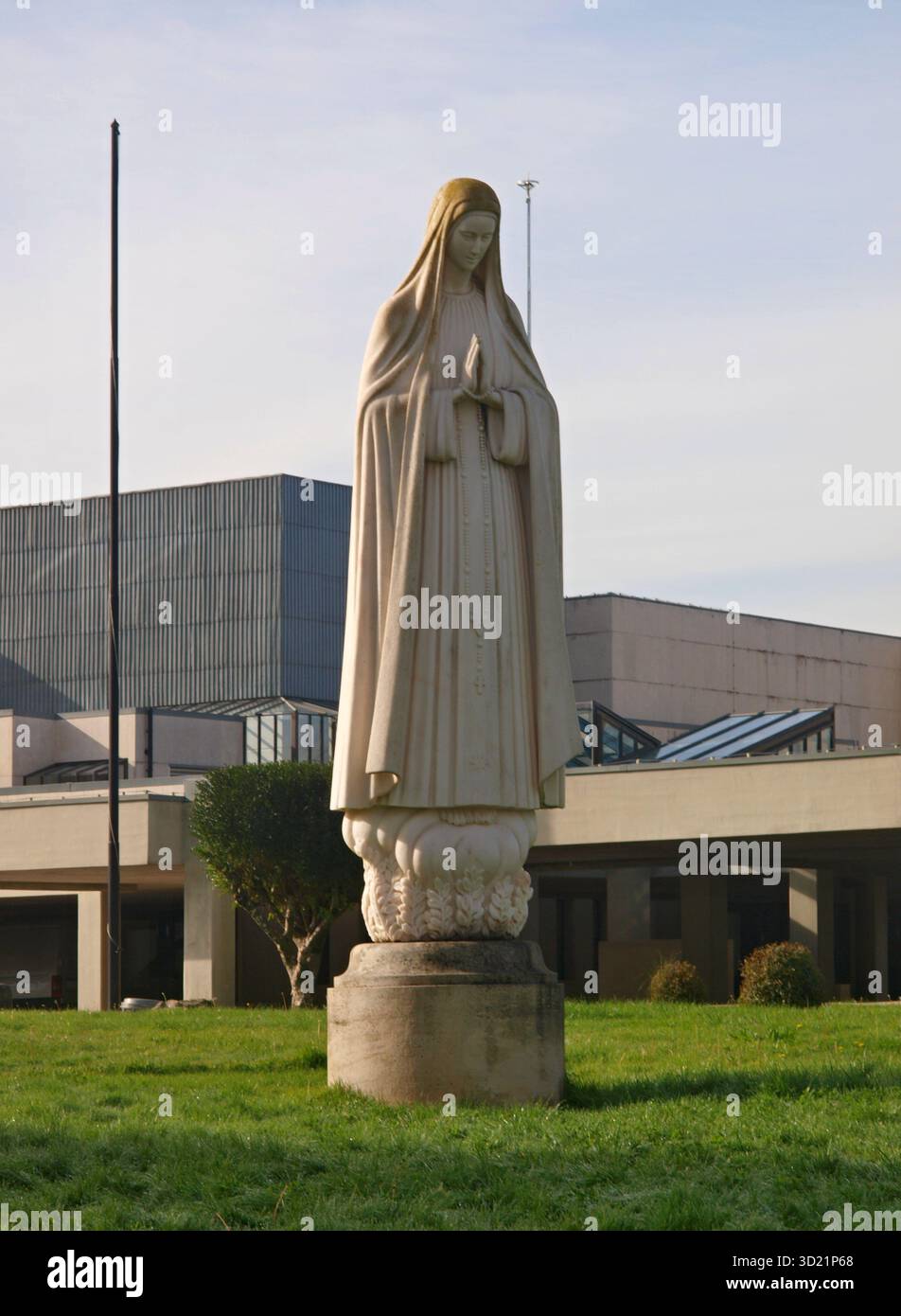 Statue de la Vierge Marie priant devant une église moderne Banque D'Images