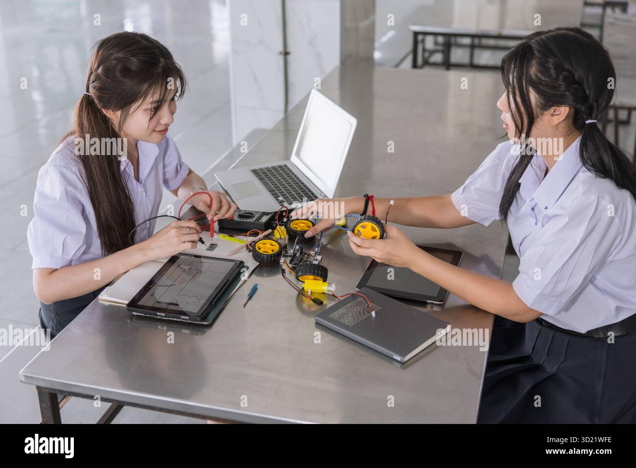 Les étudiants intelligents adolescents dans le STEM d'apprentissage uniforme avec composant de carte de circuit imprimé d'électricité iot sur le campus scolaire moderne à l'intérieur. Banque D'Images