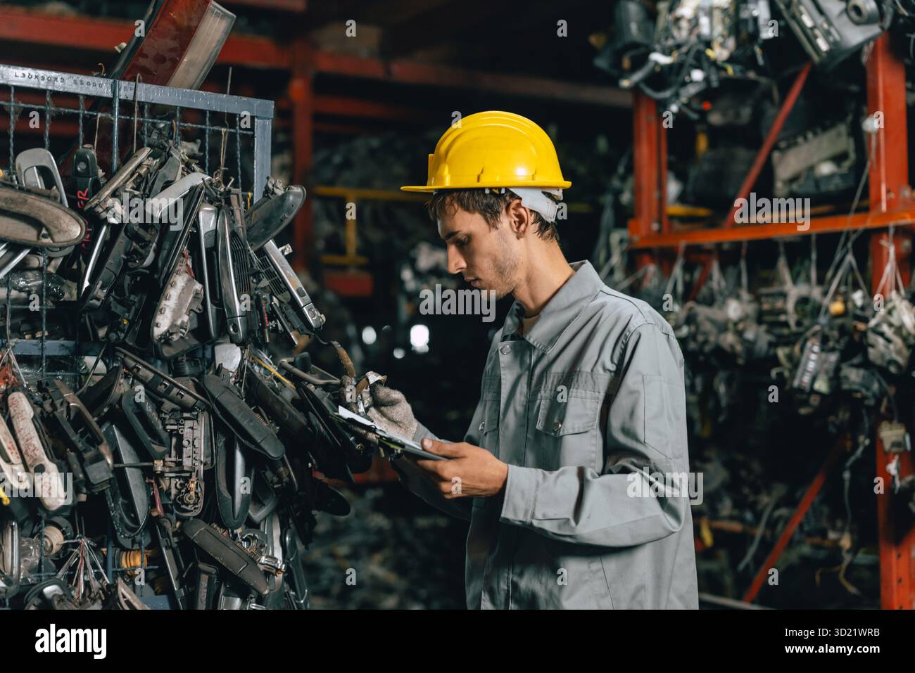 Technicien ouvrier masculin travaillant dans l'entrepôt d'atelier de vieil atelier de pièces de voiture de cour de ferraille de garage Banque D'Images